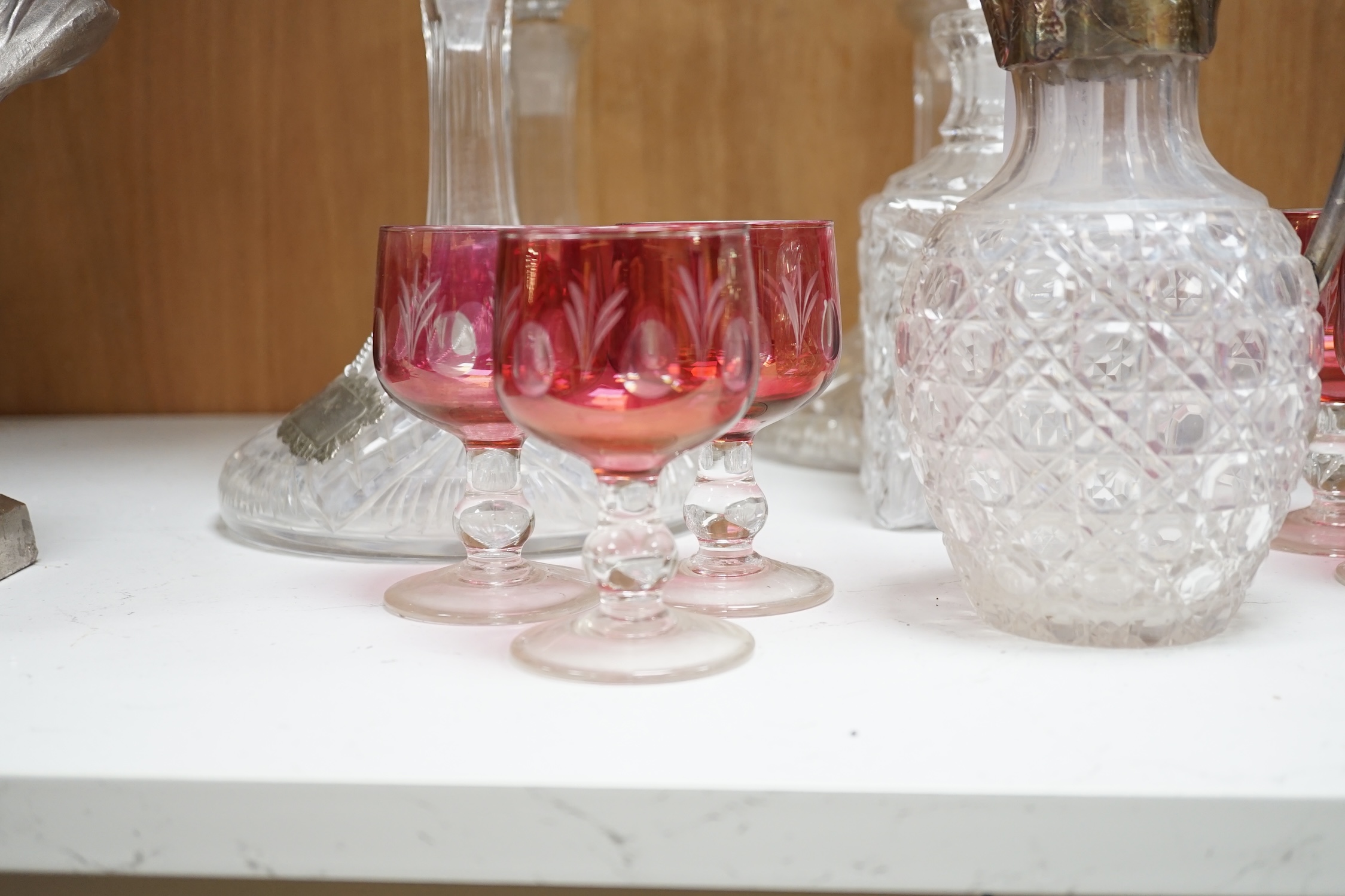 Two pairs of cut glass ships decanters, a square decanter, a ewer and a tall Scottish decanter and six cranberry glasses, tallest 43cm high